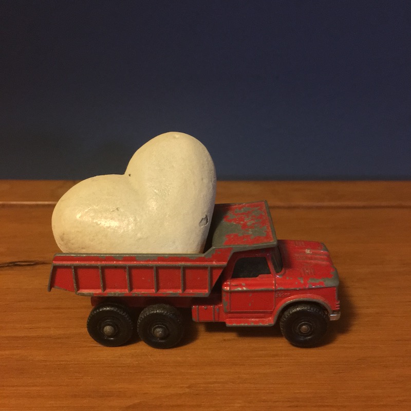 photo of a toy red dump truck with a white metal heart in the back