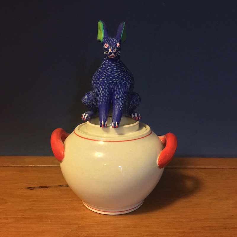 photo of a ceramic sugar bowl with a blue Mexican wood carving of a rabbit